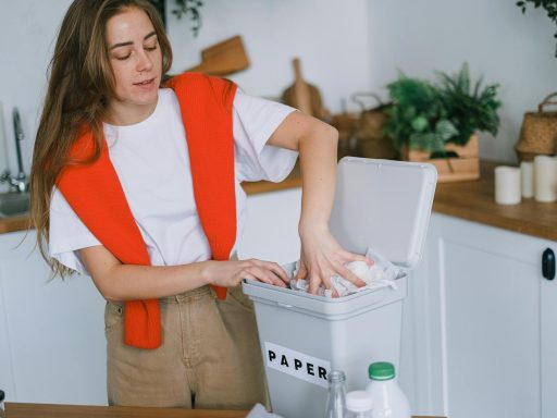 Young woman organizes recyclable paper in her kitchen for zero waste lifestyle.