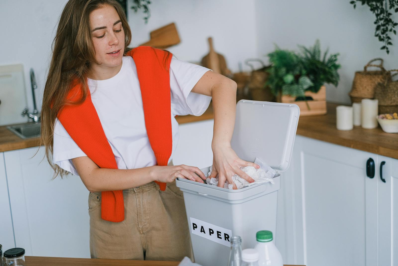 Young woman organizes recyclable paper in her kitchen for zero waste lifestyle.