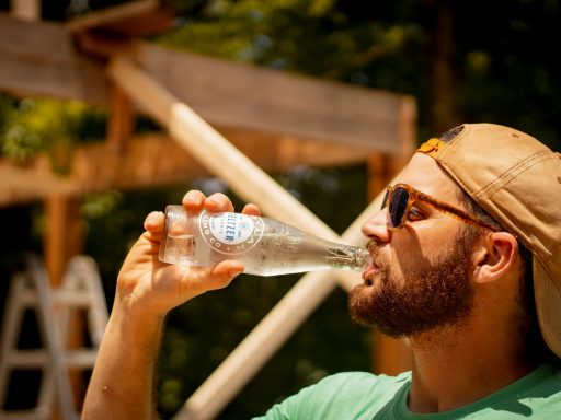 man in green crew neck shirt holding clear plastic bottle