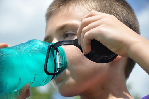 Persoon die op een warme zomerdag water drinkt uit een fles