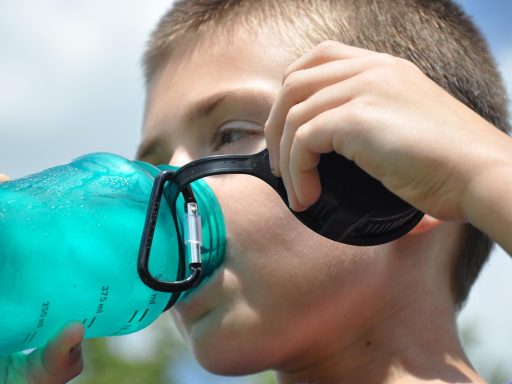 Persoon die op een warme zomerdag water drinkt uit een fles