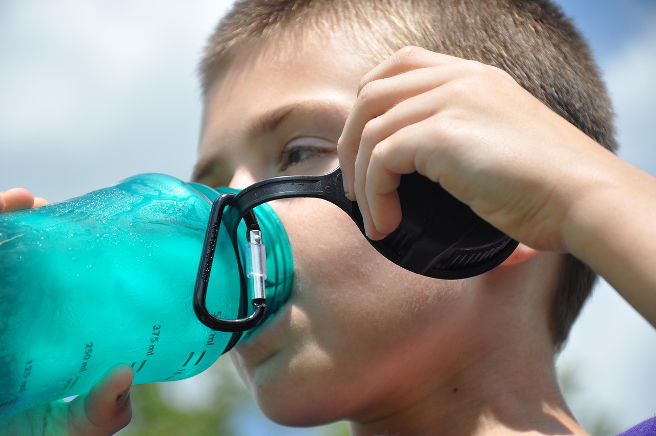 Persoon die op een warme zomerdag water drinkt uit een fles