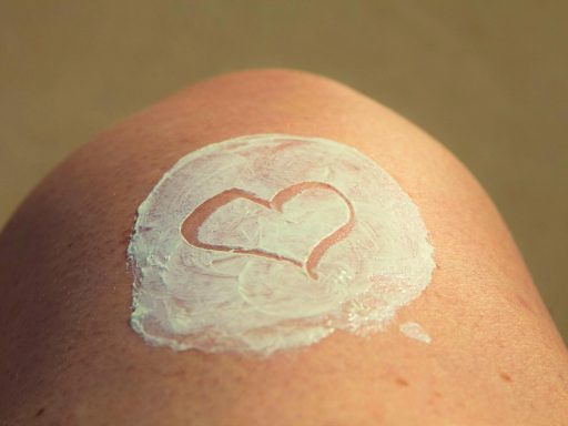 Persoon die zonnebrand aanbrengt op de schouder op een zonnig strand