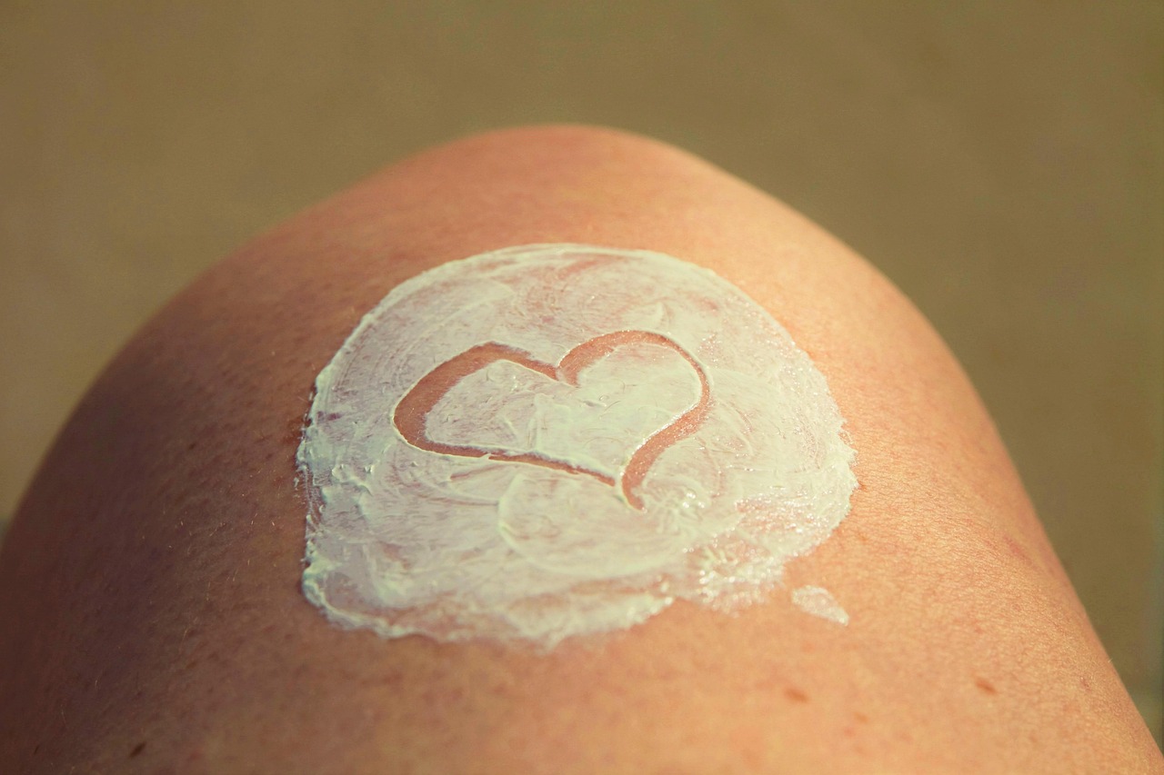 Persoon die zonnebrand aanbrengt op de schouder op een zonnig strand
