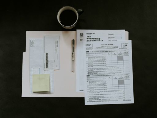 Tax forms, a pen, and a coffee mug on a dark desk