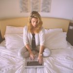 Persoon werkt aan laptop op een warme zomerdag met zonlicht door het raam