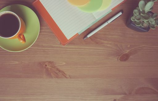 Freelancer die zijn maandelijkse inkomsten bijhoudt in een notitieboek aan een bureau