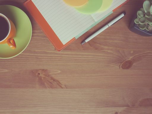 Freelancer die zijn maandelijkse inkomsten bijhoudt in een notitieboek aan een bureau