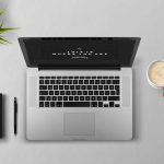 Persoon die gefrustreerd naar een laptop kijkt met een notitieboek op het bureau