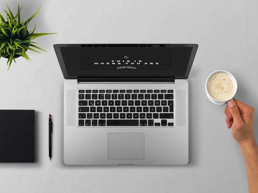 Persoon die gefrustreerd naar een laptop kijkt met een notitieboek op het bureau